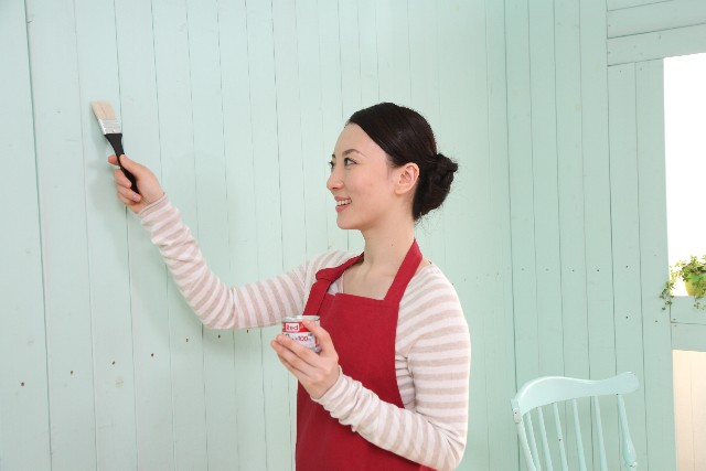 壁にペンキを塗る女性